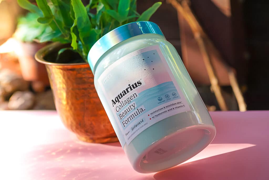 A collagen supplement in front of potted plant in bronze jar with dramatic lighting.