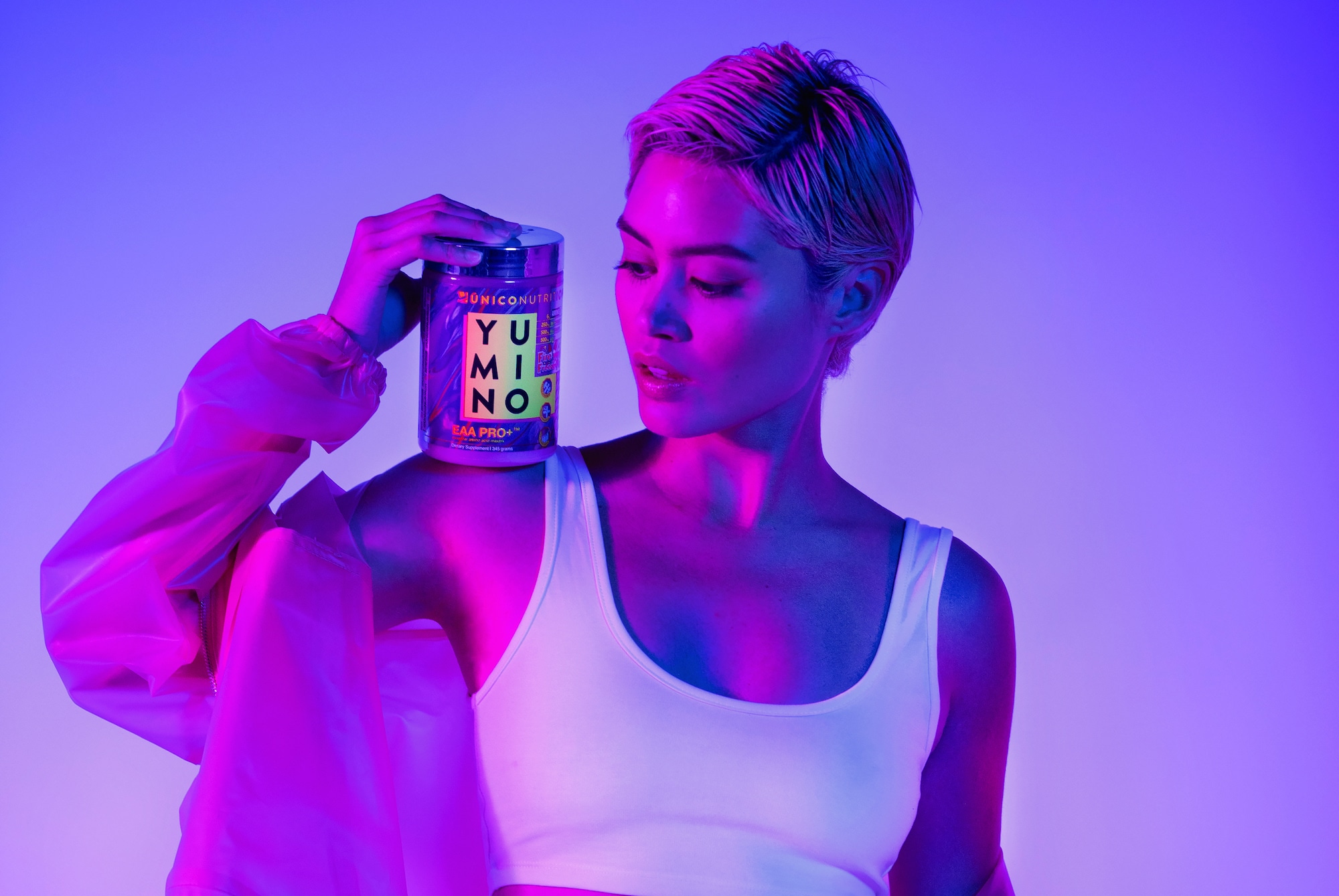 trendy woman holding jar of amino acids on her shoulder, with moody purple lighting