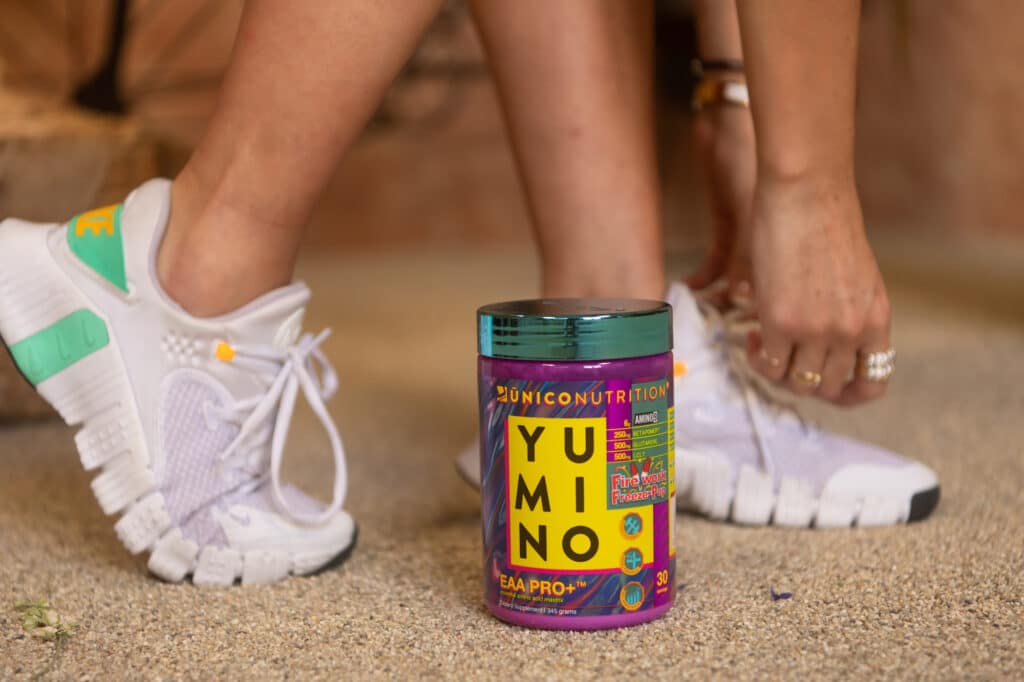 woman tying shoes preparing for a running workout with amino acids in foreground.