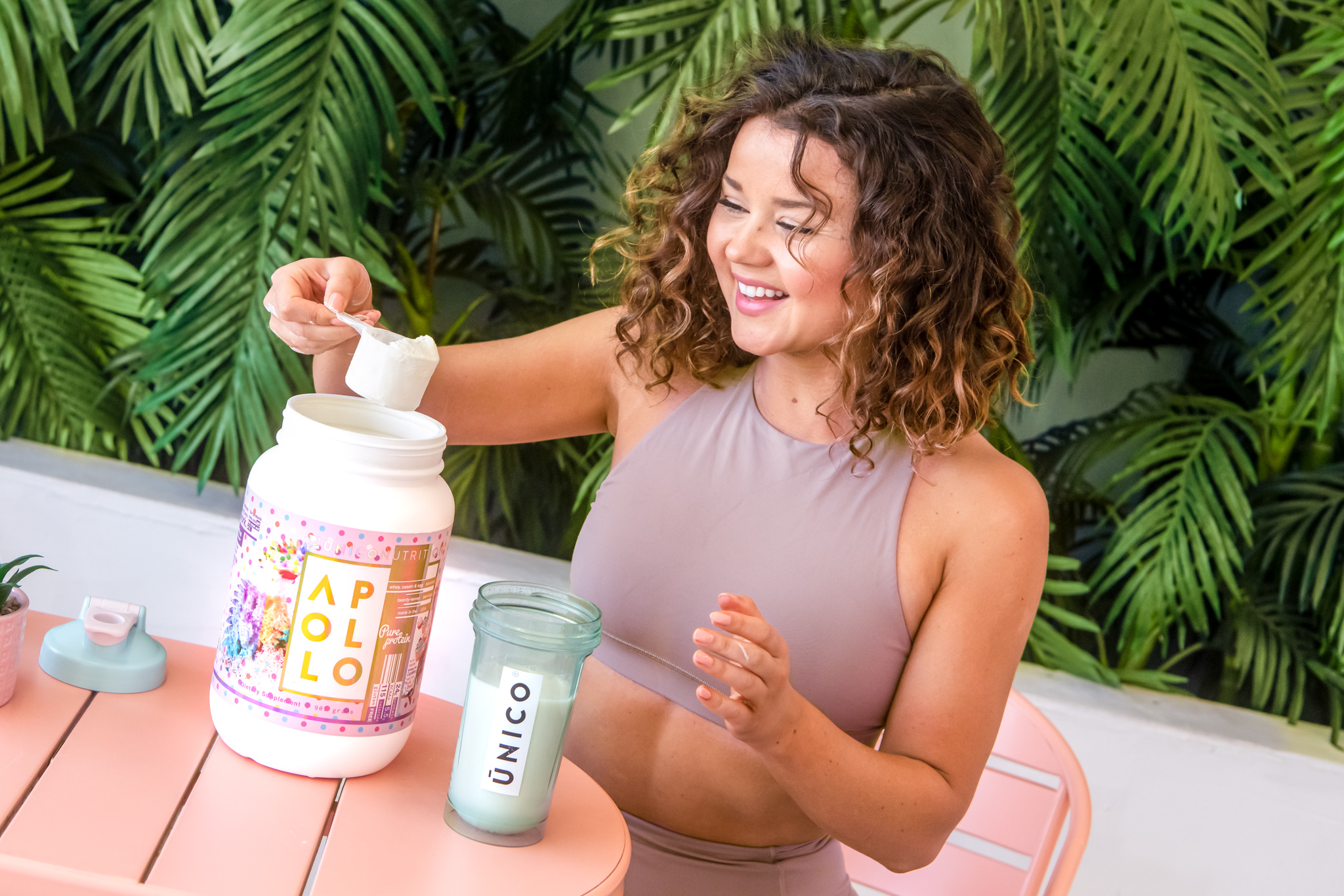 girl scooping protein from protein powder jar