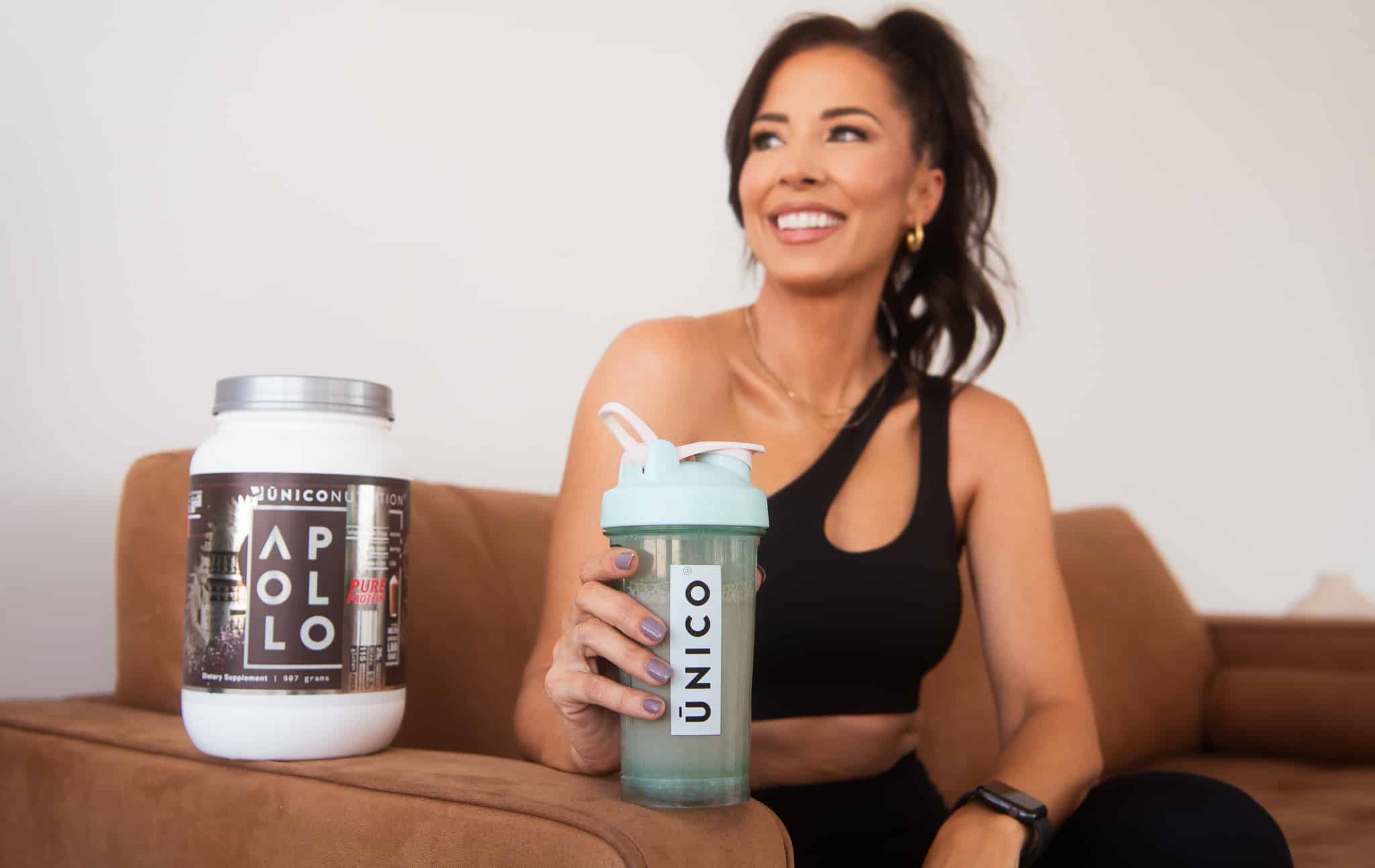 woman on couch sipping protein shake