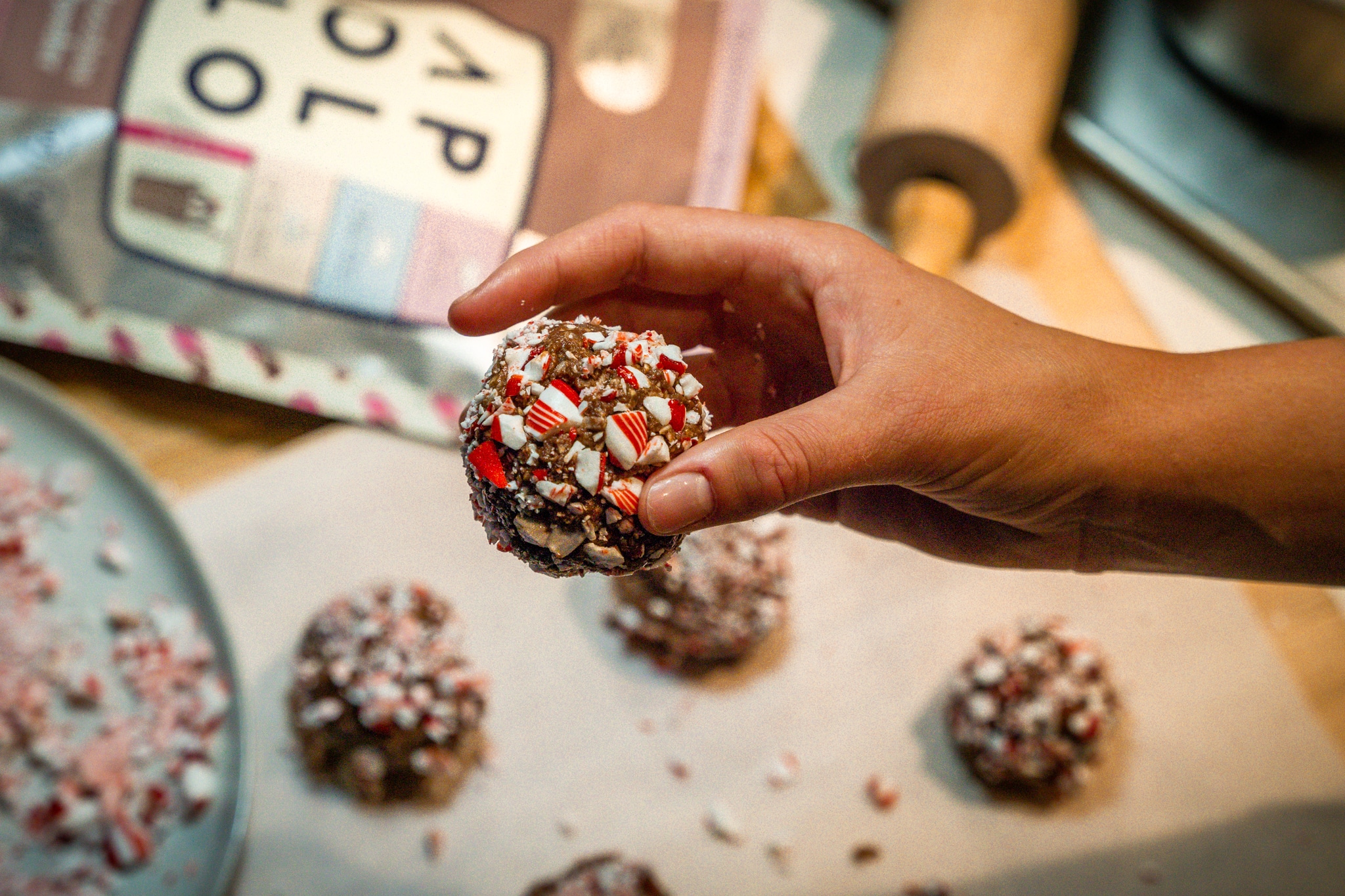 woman's hand holding a homemade protein ball snack with candy cane coating